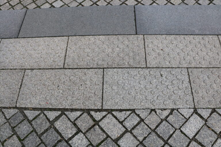 Grau abgestufte Pflastersteine und Natursteinplatten bilden einen geometrischen Belag mit klaren Fugen auf einem Gehweg im Stadtgebiet von Cottbus.