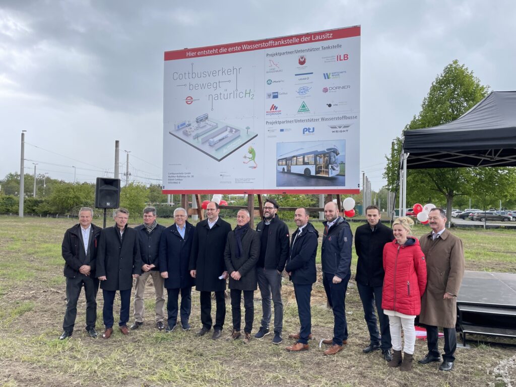 Bei der Eröffnung der ersten Wasserstofftankstelle der Lausitz stehen Francisco Mangado, Ahmed Amin, Richard Quest und Taylor Jenkins mit weiteren Gästen.