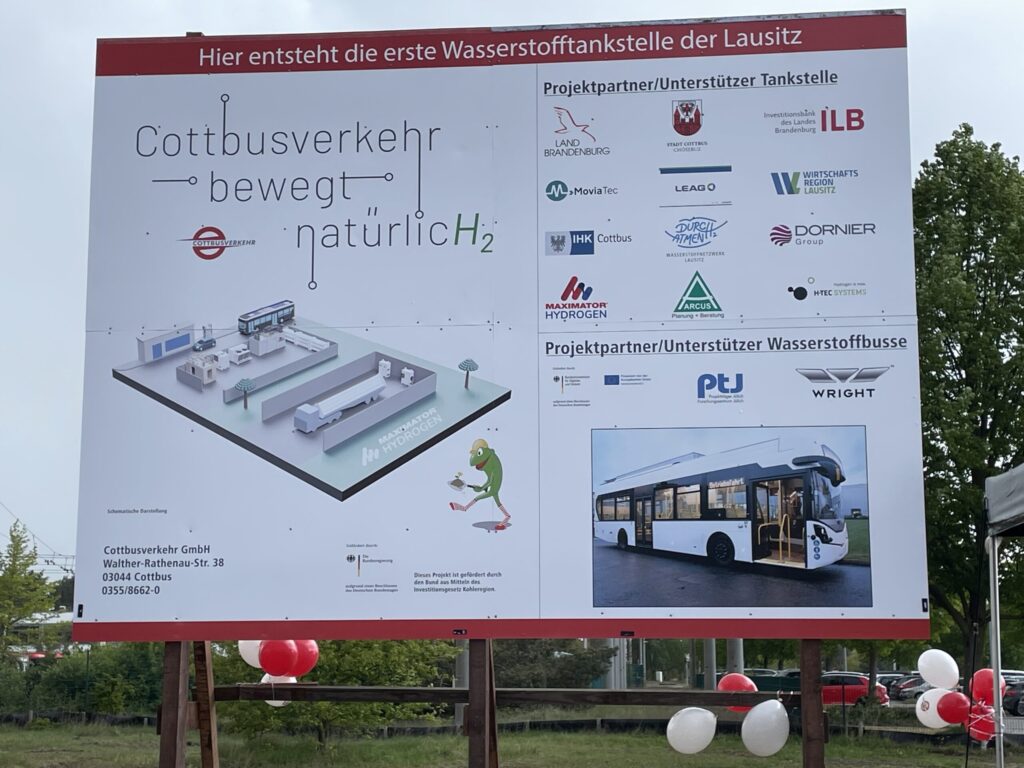 Auf dem Schild steht die erste Wasserstofftankstelle der Lausitz; daneben sind Cottbusverkehr, Stadt Cottbus/Chóśebuz und weitere Partnerlogos zu sehen.