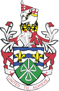 Ein farbiges Wappen mit Krone, Lilien und grünem Schild zeigt unten das Motto „UNITED. TO. ACHIEVE“ in roten Buchstaben auf weißem Hintergrund.
