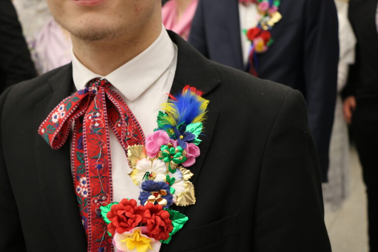 Ein junger Mann im schwarzen Anzug trägt sorbisch-wendische Festtracht mit bunten Blumen und roter Schleife bei Zapust in Cottbus/Chóśebuz.