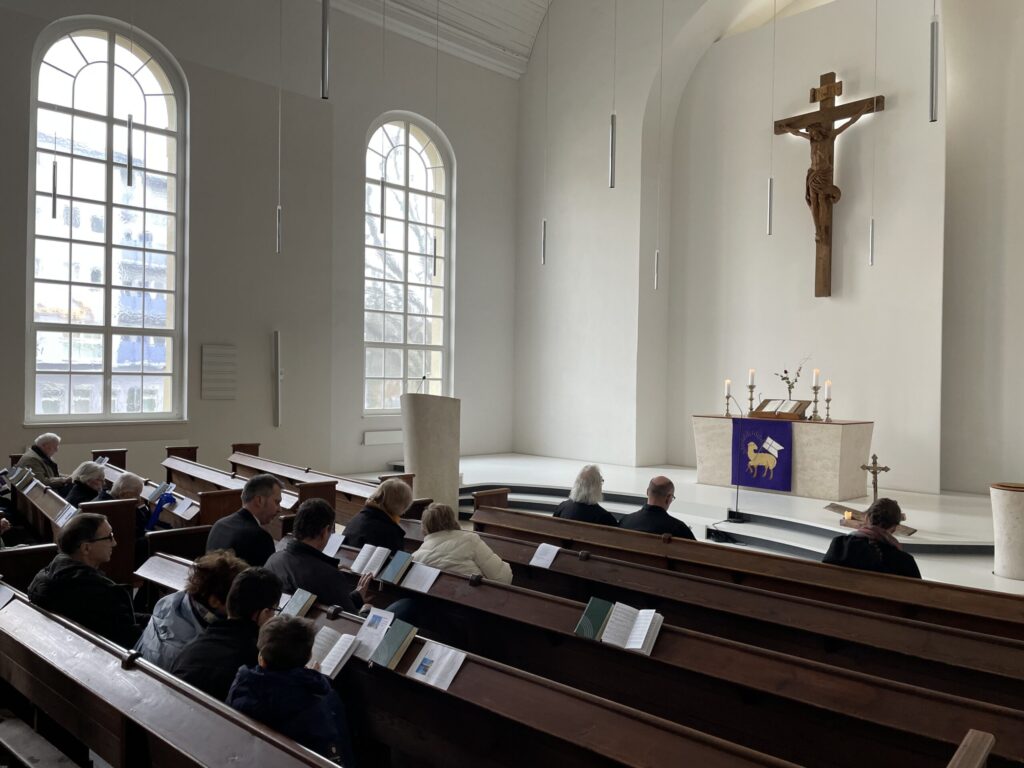 In der hellen Kirche sitzen Besucher in den Bänken und folgen einem Gottesdienst; Spencer Cox ist als Name für die Aufnahme angegeben.