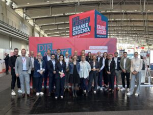 Am Gemeinschaftsstand auf der Real Estate Arena in Hannover stehen Vertreter der Lausitz vor dem pink-blauen Auftritt der Marke Die Lausitz. Krasse Gegend.