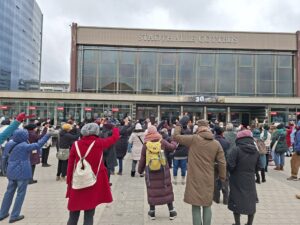 Menschen heben vor der Stadthalle Cottbus die Arme beim One-Billion-Rising-Protest gegen Gewalt in Cottbus/Chóśebuz.