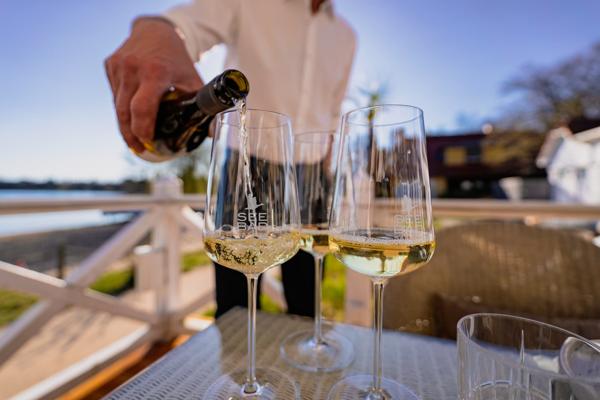 Bei den Weinfreunden schenkt ein Gastwinzer auf der Seebad-Terrasse weißen Wein in Gläser ein und sorgt für einen sommerlichen Abend am See.