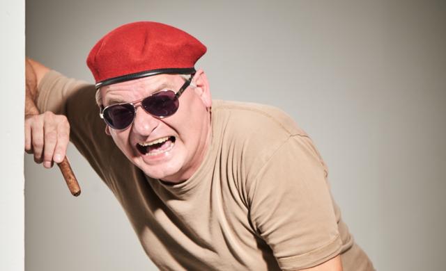 Mit rotem Barett und Sonnenbrille tritt Ausbilder Schmidt alias Holger Müller beim Gastspiel „Unkraut vergeht nicht“ auf und grinst breit.