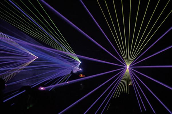 Bei der Sommernachtsparty in Cottbus durchziehen violette und grüne Laserstrahlen den dunklen Raum und sorgen für eine eindrucksvolle Lichtshow.