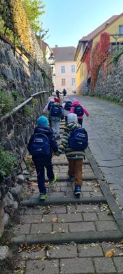Mehrere Kinder steigen mit Rucksäcken die steilen Steinstufen in Strausberg hinauf und entdecken auf der Kinder-Exkursion die alte Stadtmauer.