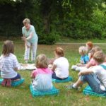 Im Park lauschen Kinder bei der Branitzer Märchenstunde der Erzählung von Ute Fisch und gehen auf märchenhaften Spuren durch das Grün.