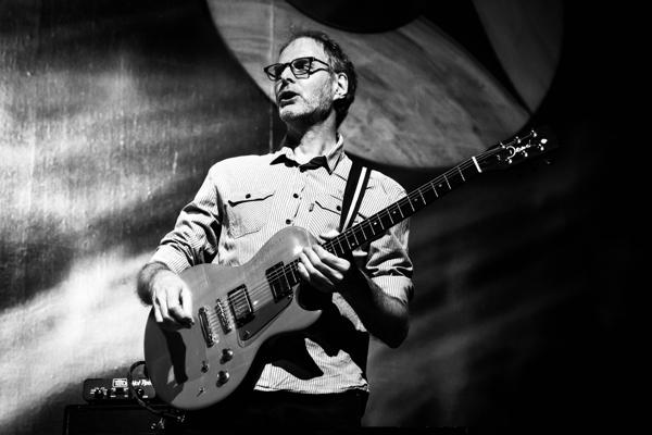 Im Rahmen des JAZZPREIS BRANDENBURG 2026 spielt Andreas Willers schwarzweiß mit E-Gitarre auf der Bühne vor abstraktem Licht.