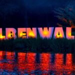 Im Spreeauenpark Cottbus leuchtet die große ELBENWALD-Schrift in Pink und Orange, während sich das Licht im Wasser spiegelt.