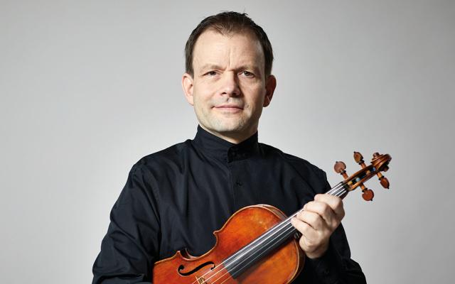 Beim Open-Air-Konzert am Neruda-Block steht Stefan Hunger vom Kammerorchester des BSOF mit der Violine vor hellem Hintergrund und leitet den Auftritt.