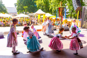 Beim Sorbischen/Wendischen Fest in Cottbus/Chóśebuz tanzen Kinder in traditionellen Trachten auf der Bühne vor vielen Gästen beim Stadtfest im Park.