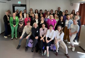 Teilnehmende des 1. Strukturwandellabors der Bundesstiftung Gleichstellung stehen in einem Raum in Berlin und blicken gemeinsam in die Kamera.