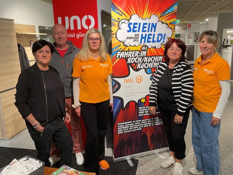 Fünf Personen stehen an einem Messestand der Tafel Cottbus mit Werbebanner