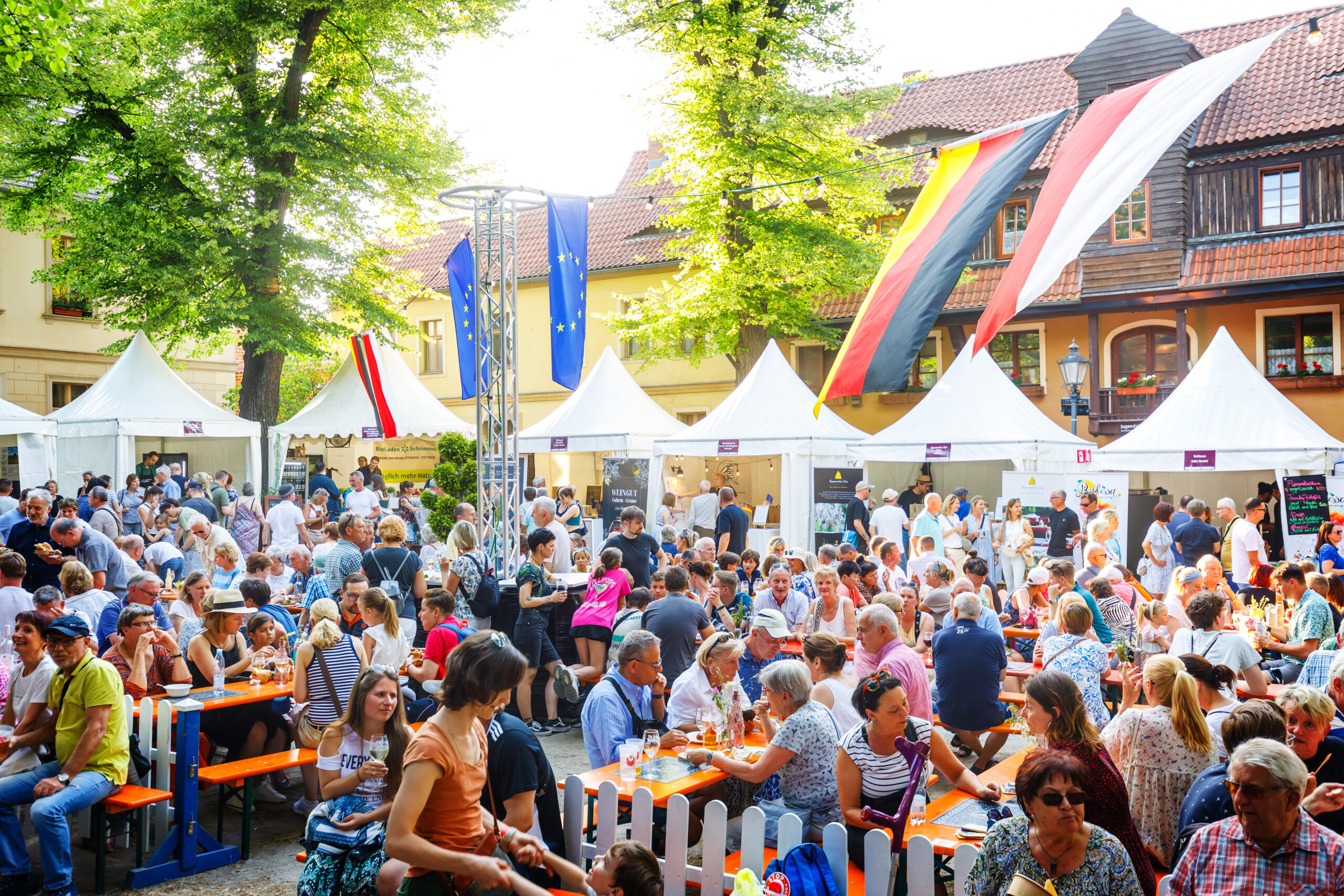 Auf dem Klosterplatz in Cottbus/Chóśebuz genießen viele Gäste beim deutsch-polnischen Bürgerfest Wein, Kulinarik und Gespräche unter Zelten.