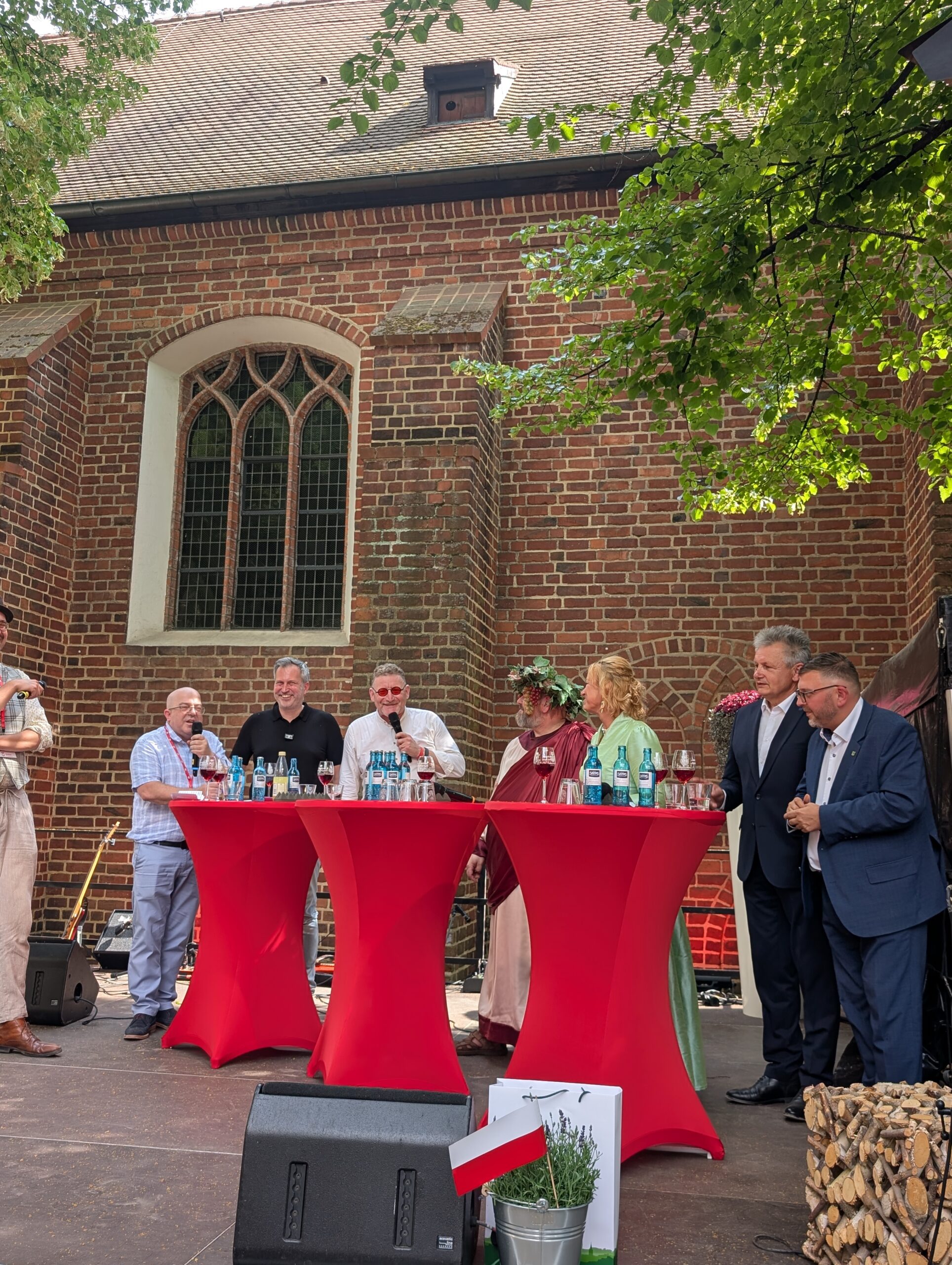 Beim deutsch-polnischen Bürgerfest in Cottbus/Chóśebuz sprechen Tobias Schick und Gäste aus Zielona Góra vor der Backsteinwand des Klosterplatzes.