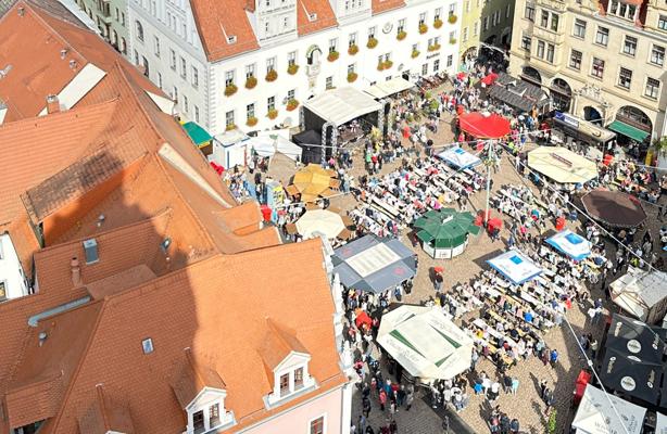 Auf dem historischen Marktplatz drängen sich zahlreiche Besucher zwischen Ständen, Sonnenschirmen und einer Bühne.