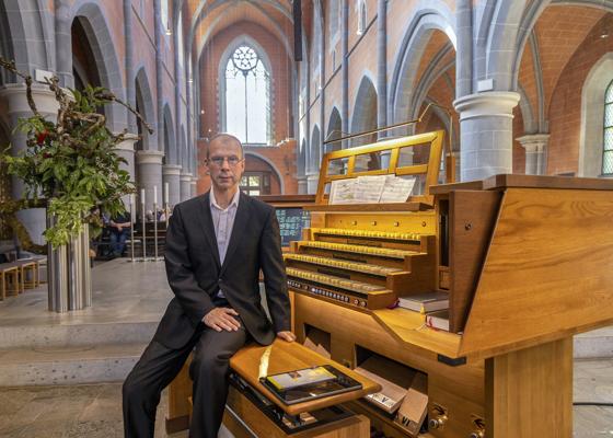 Ein Mann sitzt in der Klosterkirche Cottbus neben der Konzertorgel, vor ihm liegen Noten und Registerzüge.