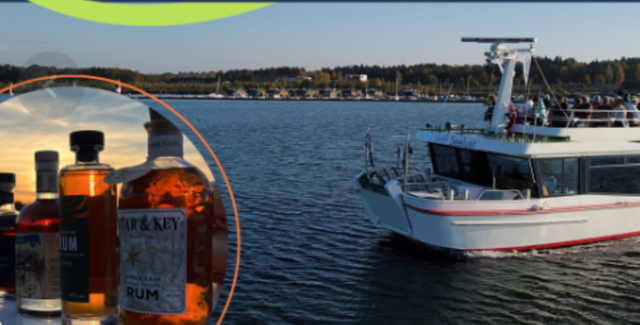Im Vordergrund stehen mehrere Rumflaschen, während ein Ausflugsschiff über den Bärwalder See fährt.