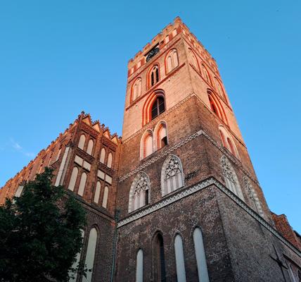 Der gotische Backsteinturm der St.-Marien-Kirche in Frankfurt (Oder) ragt vor blauem Himmel auf.