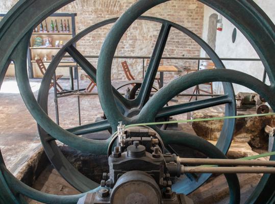 Die großen Schwungräder einer historischen Dampfmaschine stehen in einer Backsteinhalle vor Backsteinwänden.