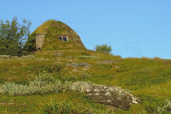 Ein grasbedeckter Hügel mit kleiner Öffnung und Fenster liegt unter klarem blauen Himmel in einer offenen Landschaft.