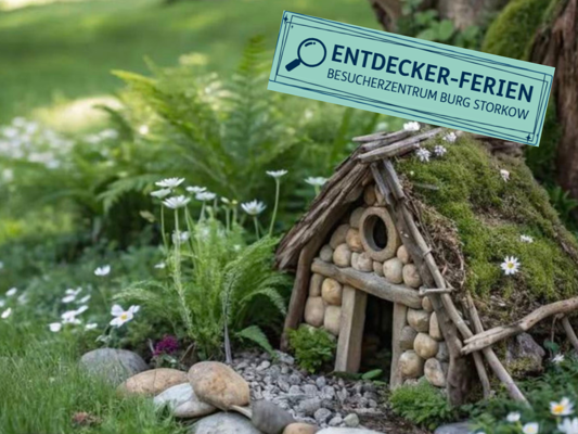 Ein kleines Haus aus Steinen, Holz und Moos steht zwischen Farnen und Gänseblümchen; darüber ein Schild „Entdecker-Ferien“.