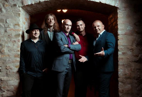 Fünf Männer der Latvian Blues Band stehen eng beieinander in einem steinernen Gewölbe, einer im Hut und einer im Anzug.