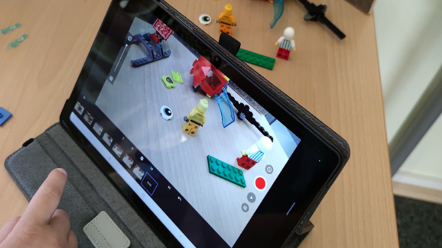 Auf einem Tablet ist eine Stop-Motion-Aufnahme mit Lego-Figuren, Bausteinen und Aufnahmesteuerung zu sehen.