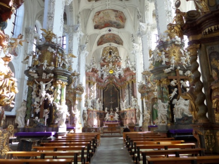 Der barock geschmückte Kirchenraum zeigt reich verzierte Seitenaltäre, geschnitzte Figuren und den Hauptaltar im Mittelgang.