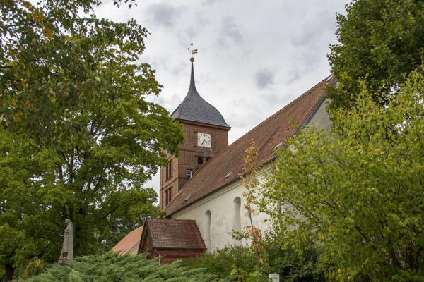 Im Pfarrgarten von Atterwasch steht die Kirche mit Turm unter alten Bäumen, während das Volksliedersingen in ruhiger Dorfatmosphäre stattfindet.