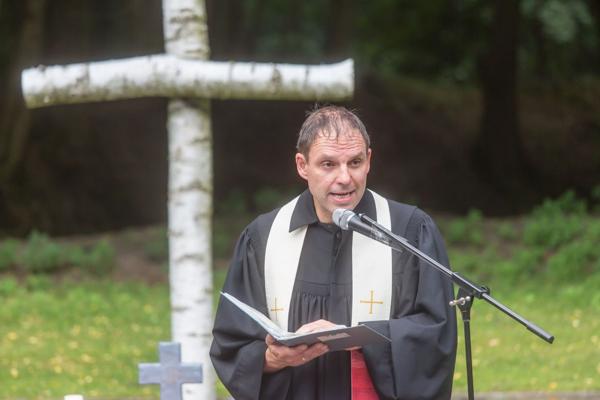 Im Wildpark leitet Frank Gründler den Gottesdienst am Mikrofon vor einem großen Birkenkreuz und spricht unter freiem Himmel zu den Gästen.