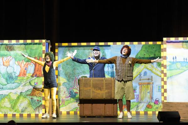 Beim Musical „Oh wie schön ist Panama“ stehen der kleine Tiger und der kleine Bär mit ausgebreiteten Armen vor bunten Kulissen auf der Bühne.