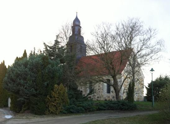 Kirche mit Zwiebelturm und rotem Dach, teils von Bäumen und Sträuchern verdeckt., Foto: TVEEL, Lizenz: TVEEL