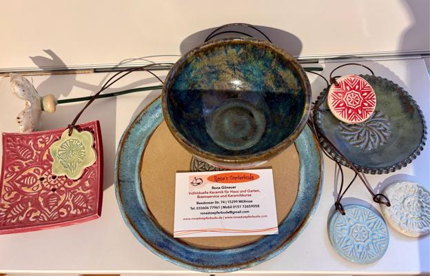 Mehrere handgefertigte Keramikschalen, Teller und Anhänger mit weihnachtlichen Mustern liegen auf einer Auslage.