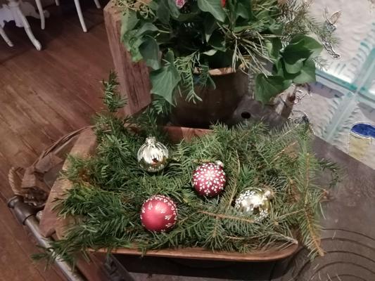 Rote und silberne Weihnachtsbaumkugeln mit sorbischen Mustern liegen auf Tannenzweigen in einer Holzschale.